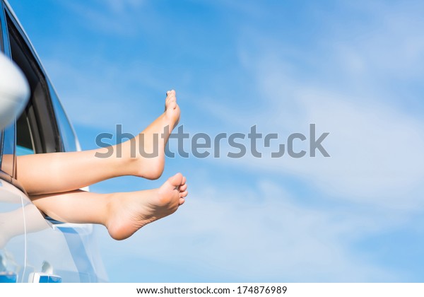 feet of a young girl from the window of a car on a
background of blue sky