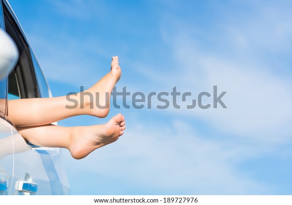 feet of a young girl from the window of a car on a\
background of blue sky