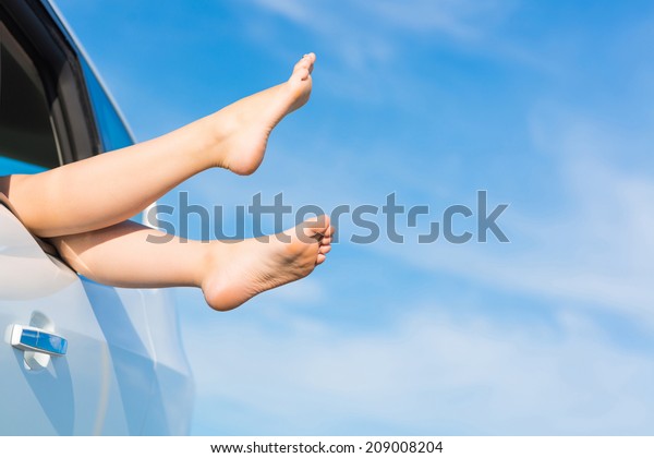 feet of a young girl from the window of a car on a\
background of blue sky