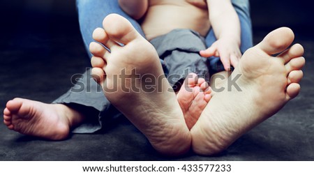 feet of a young mother and her baby, wearing jeans and sitting on the floor