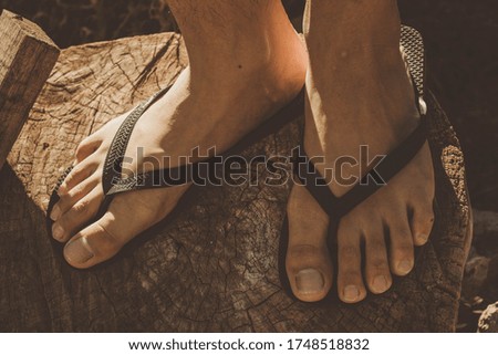 feet of a young person in black sandals on a dry log