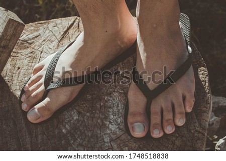 feet of a young person in black sandals on a dry log