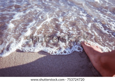 Feet of a young woman on the beach, near the water