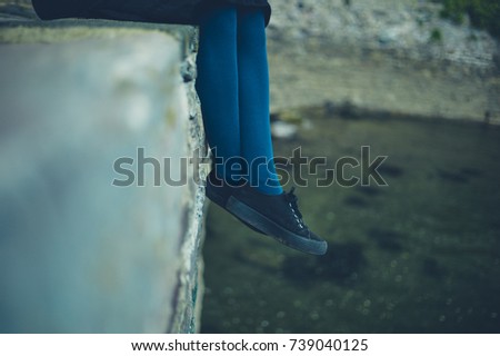 The feet of a young woman relaxing on a ledge by the river