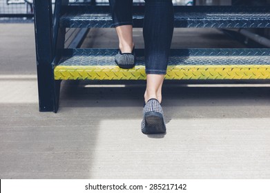 The Feet Of A Young Woman As She Is Walking Up Some Metal Stairs