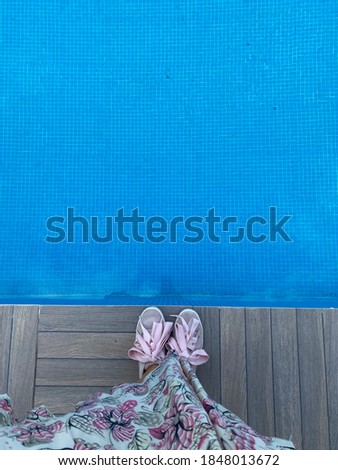 Feet of a young woman standing at the swimming pool.