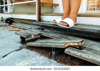 Feet of young woman wearing sandals walked down broken wooden stairs. Woman may be fell down stairs due to broken wooden leg stepladder. Ladder made of wood broke at home. Damaged wooden stepladder. - Powered by Shutterstock