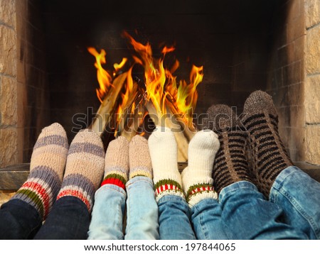 Feets of a family wearing woolen socks warming near the fireplace