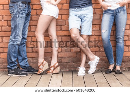 Feets of four people in different fashion style shoes at brick wall background