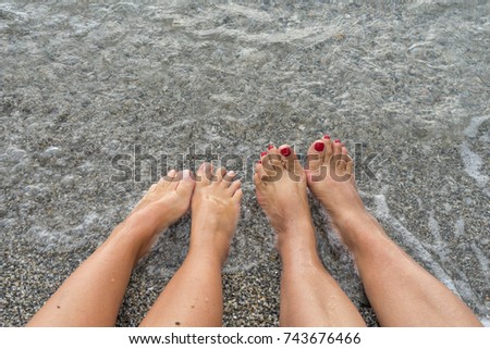 Feets relaxing at the beach in the water.