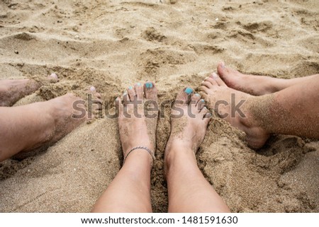 feets of three girls in the sand on the beach