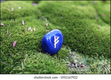 Fehu Rune made of Blue Onyx on a mossy background