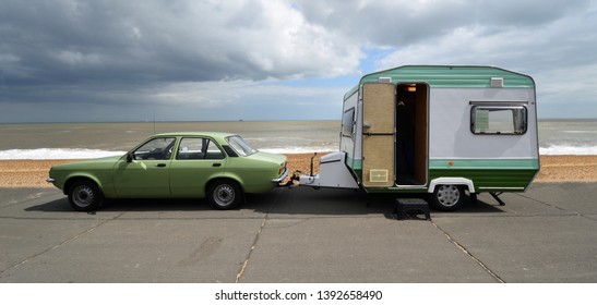 FELIXSTOWE, SUFFOLK, ENGLAND - MAY 05, 2019: Classic Green Vauxhall Chevette motor car  towing  Vintage Caravan - trailer parked on seafront promenade.