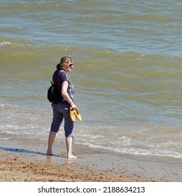 Felixstowe, Suffolk, UK - 10 August 2022 : Woman Paddling In The Sea On A Hot Summer Day.