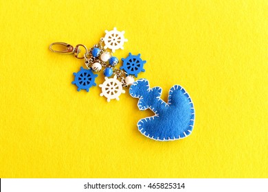 Felt Anchor Key Chain Decorated With Beads And Small Decorative Ship Wheel. Beautiful Keychain For Car Or Beach Bag Isolated On Yellow Felt Background. Charm Accessory. Summer DIY Idea 