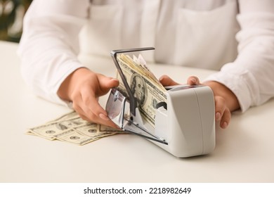 Female Accountant Using Currency Counting Machine On Light Table