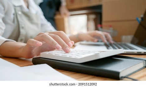 Female accountant working at desk using calculator for calculate financial report. Cropped image, closeup view.
