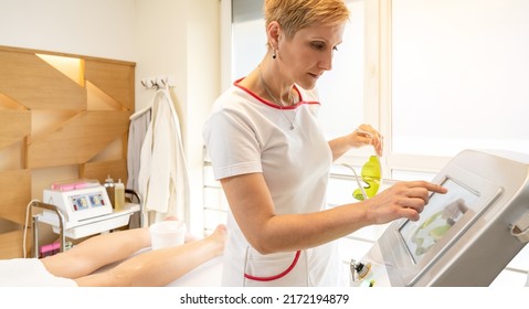 Female Aesthetician With Protective Eyeglass Setting Up Laser Diode For Epilation Procedure At Luxury Spa And Wellness Center.