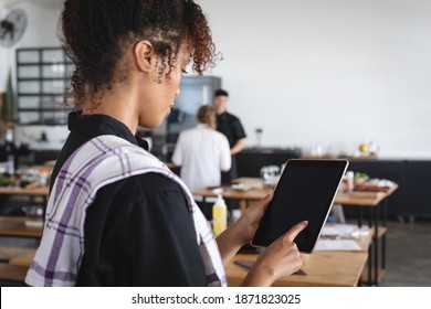 Female african american chef using digital tablet in restaurant kitchen. food preparation restaurant culinary gourmet - Powered by Shutterstock