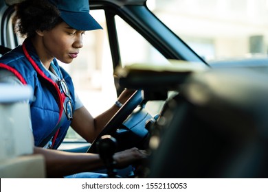 Female African American courier staring a mini van while going on package delivery.
