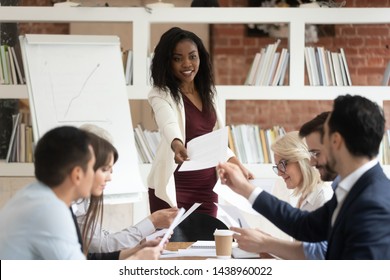 Female african coach manager give papers presenting document report business plan to team people at corporate meeting, diverse staff group and black boss do paperwork sit at office conference table - Shutterstock ID 1438960022