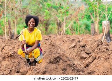 Female African Farmer Squatting And Smiling