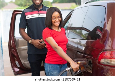 Female African Petrol Station Attendant Filling Up A Car Smiling