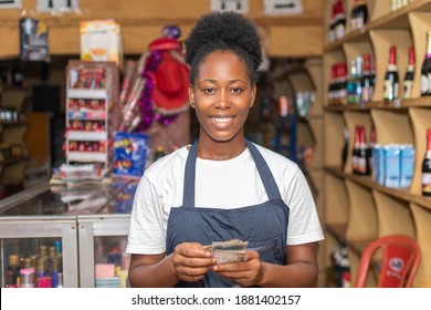 Female African Shop Attendant Smiling While Counting Money