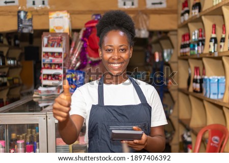 female african store attendant smiling and gives a thumbs up