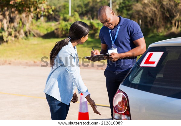 female african student driver doing pre test\
inspection in testing\
ground