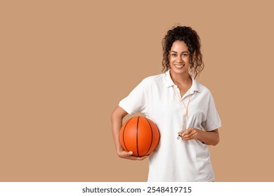 Female African-American basketball trainer with ball and whistle on beige background - Powered by Shutterstock