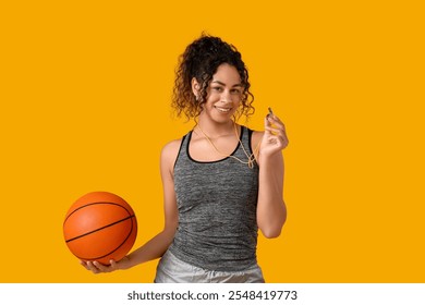 Female African-American basketball trainer with ball and whistle on yellow background - Powered by Shutterstock