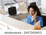 Female African-American medical intern talking by telephone at reception in clinic