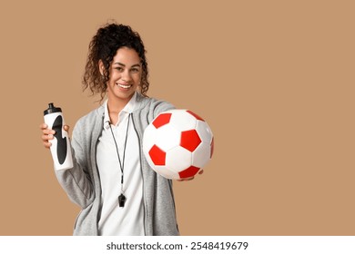 Female African-American soccer trainer with ball and water bottle on beige background - Powered by Shutterstock