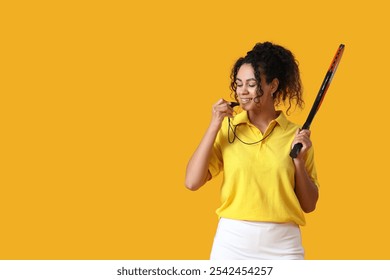 Female African-American tennis trainer with racket blowing in whistle on yellow background - Powered by Shutterstock