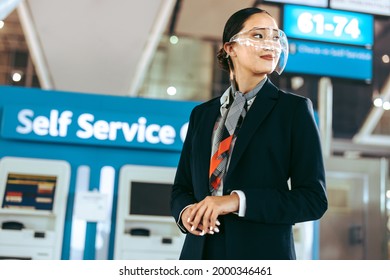 Female Airport Employee In Uniform And Face Shield Looking Away. Airport Ground Staff Working During Pandemic.