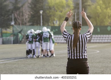 Female American Football Referee And Blurred Players In The Background 