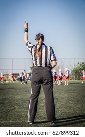 Female American Football Referee And Blurred Players In The Background