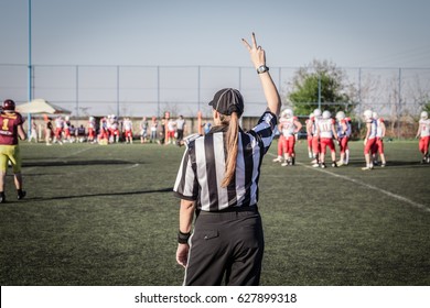 Female American Football Referee And Blurred Players In The Background