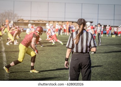 Female American Football Referee And Blurred Players In The Background