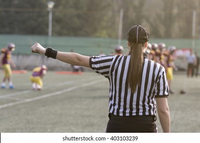 Female American Football Referee Giving Signals And Blurred Players In The Background