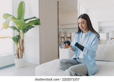 Female Amputee Holding Carbon Hand And Connecting It To Arm. Woman  Getting Used To New Bionic Prosthesis. Caucasian Girl Has Electronic Robotic Limb. Scandinavian Interior At Home.