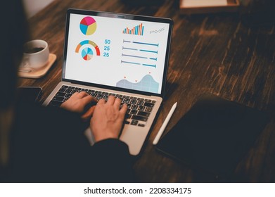 A female analyst works on a laptop showing statistics, graphs, and charts. Working on a wooden table in the creative office. Smart working. - Shutterstock ID 2208334175