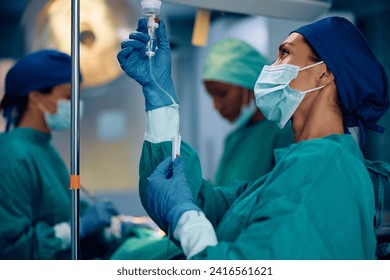 Female anesthesiologist checking patient's IV drip in the operating room at medical clinic. - Powered by Shutterstock