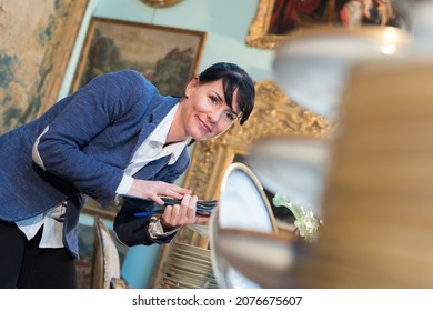 Female Antique Dealer Looking At Stock