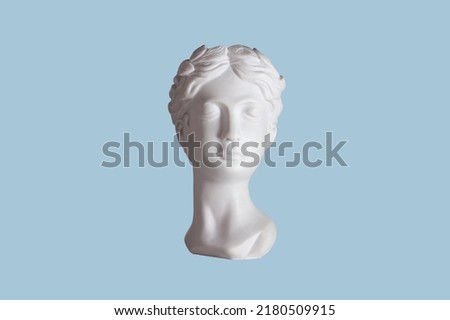 Female antique statue's head isolated on a blue color background