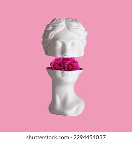 Female antique statue's head with pink flowers roses in the cut isolated on a color background. The beauty inside. Trendy collage in magazine surreal style. 3d contemporary art. Modern design
