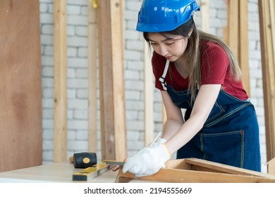 Female Apprentice Carpenter Working With Machinist Square To Measure Of Wood In The Wood Workshop