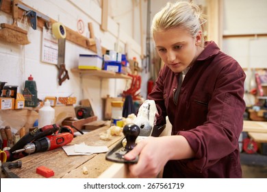 Female Apprentice Planing Wood In Carpentry Workshop