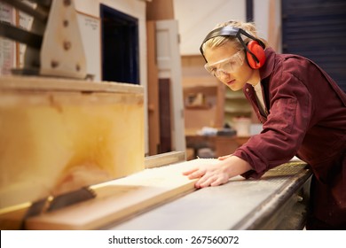 Female Apprentice Using Circular Saw In Carpentry Workshop